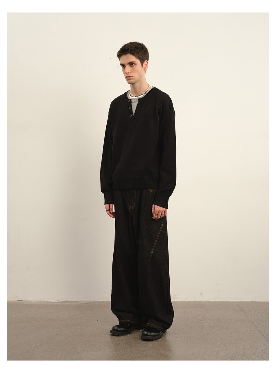 Model wearing a black long-sleeve sweater with a short buttoned neckline and dark wide-leg trousers.