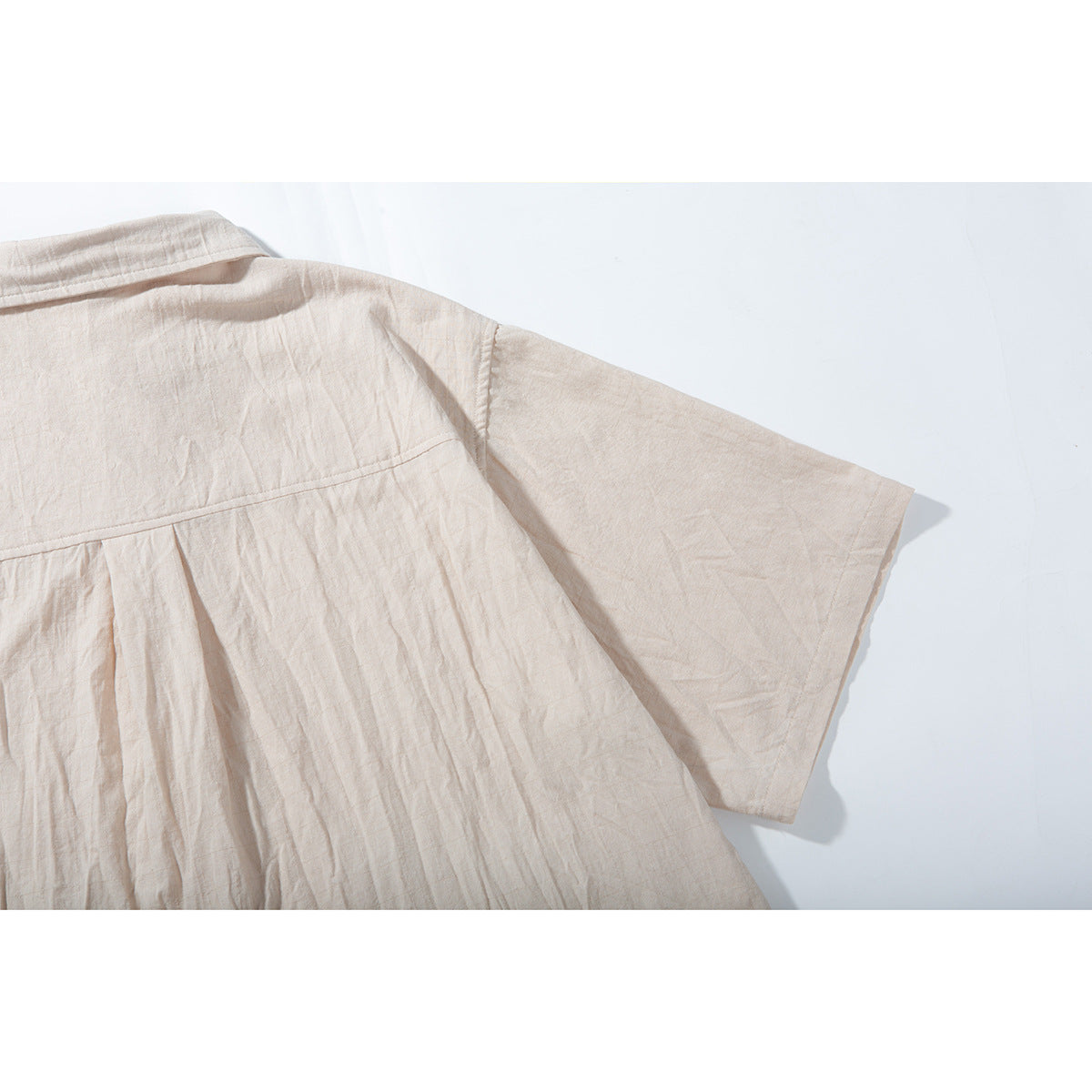 Close-up of the pale beige shirt's back yoke, pleat, and short sleeve.