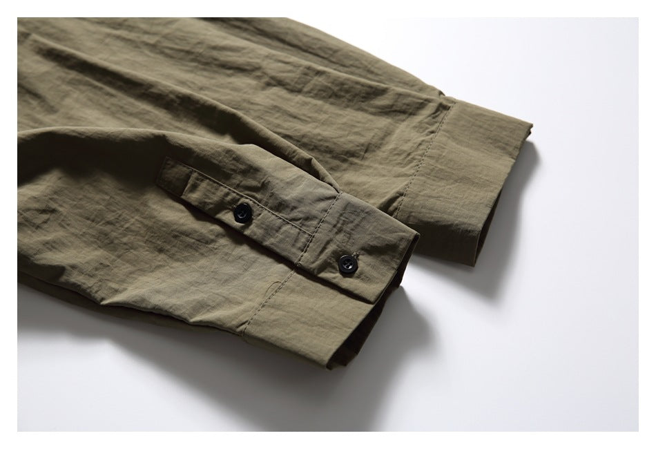 Close-up of olive-brown shirt cuffs with black buttons and stitched button tabs.