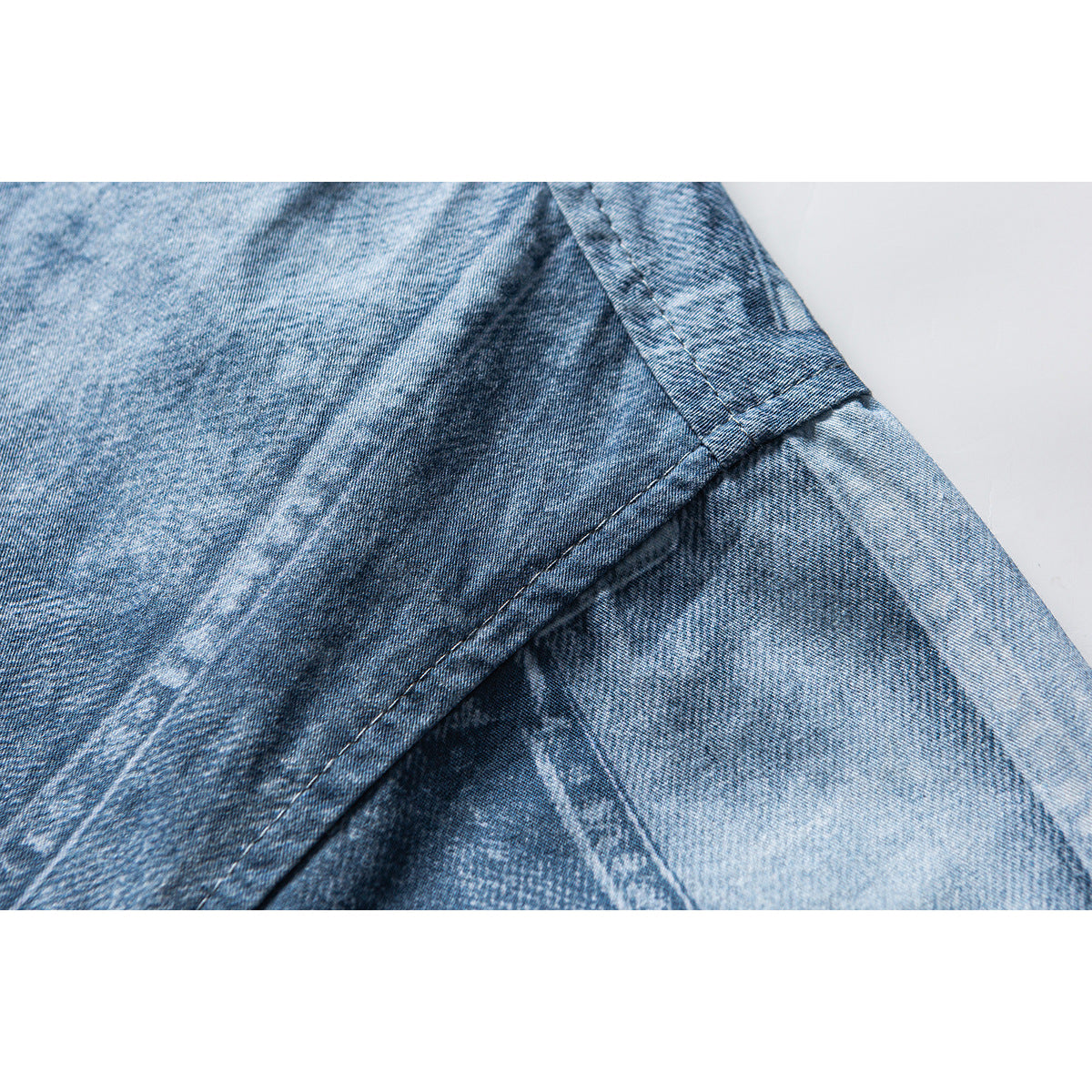 Close-up of blue washed shirt fabric and a stitched seam at the sleeve area.