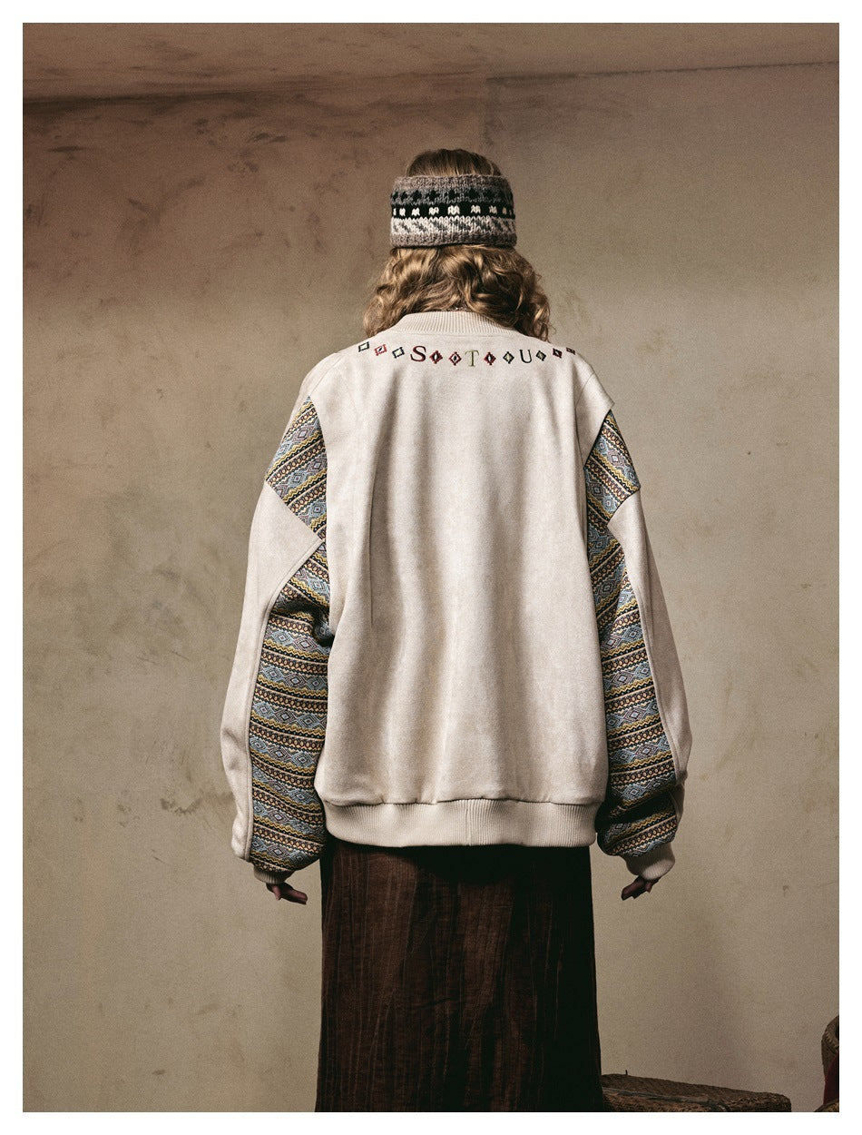 Back view of a model wearing a cream jacket with multicolor geometric patterned sleeves and embroidery across the upper back.