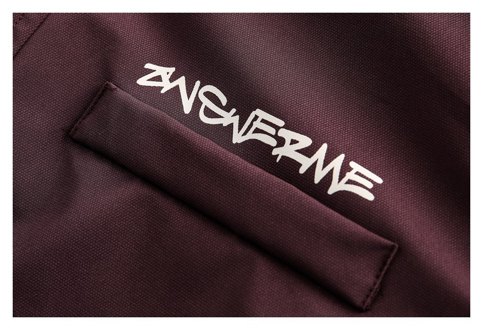 Close-up of burgundy textured fabric with white stylized lettering above a stitched flap.