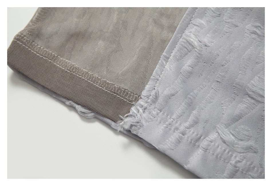 Close-up of the taupe mesh sleeve seam and its join with the textured light gray fabric.