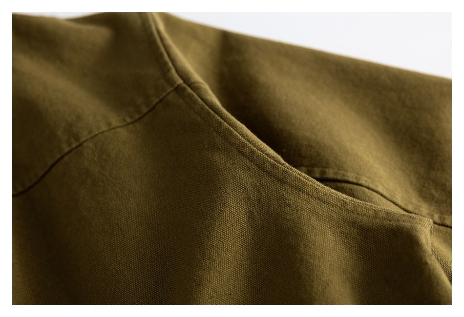 Close-up of olive-brown garment fabric showing a curved seam and construction details.