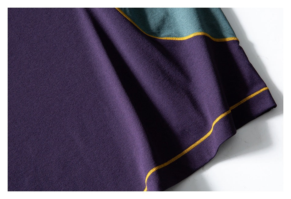 Close-up of the purple garment hem beside a teal panel, finished with mustard-yellow contrast stitching.