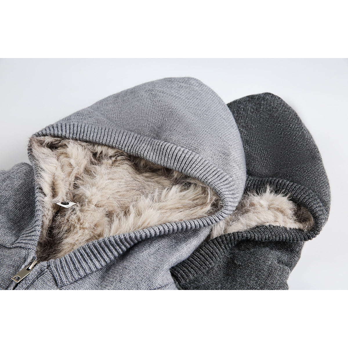 Close-up of light gray and charcoal zip-up hoodies showing ribbed hood edges and fluffy beige lining.