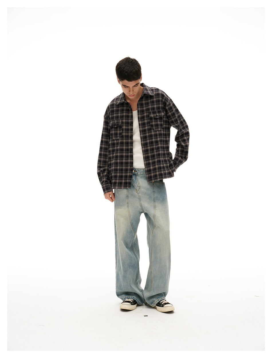 Model looking down wearing an open black plaid shirt over a white tank top with wide-leg jeans