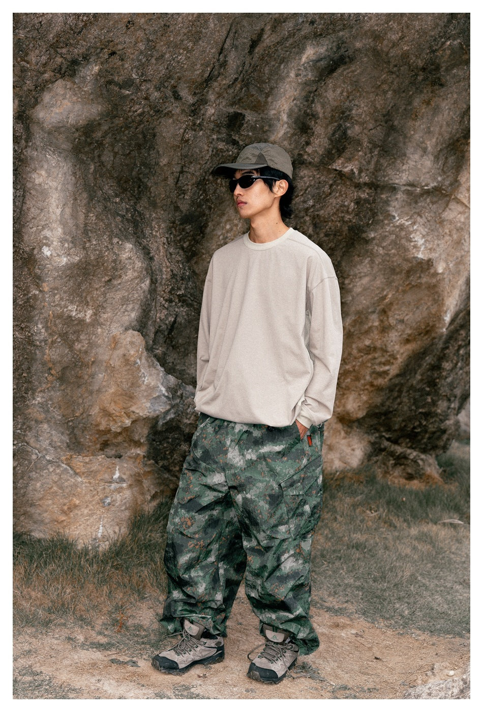 Model in profile wearing an oversized beige long-sleeve shirt and loose green camouflage trousers.