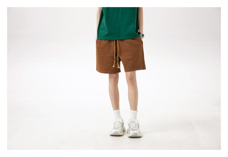 Front view of a model wearing brown drawstring shorts with a green T-shirt.