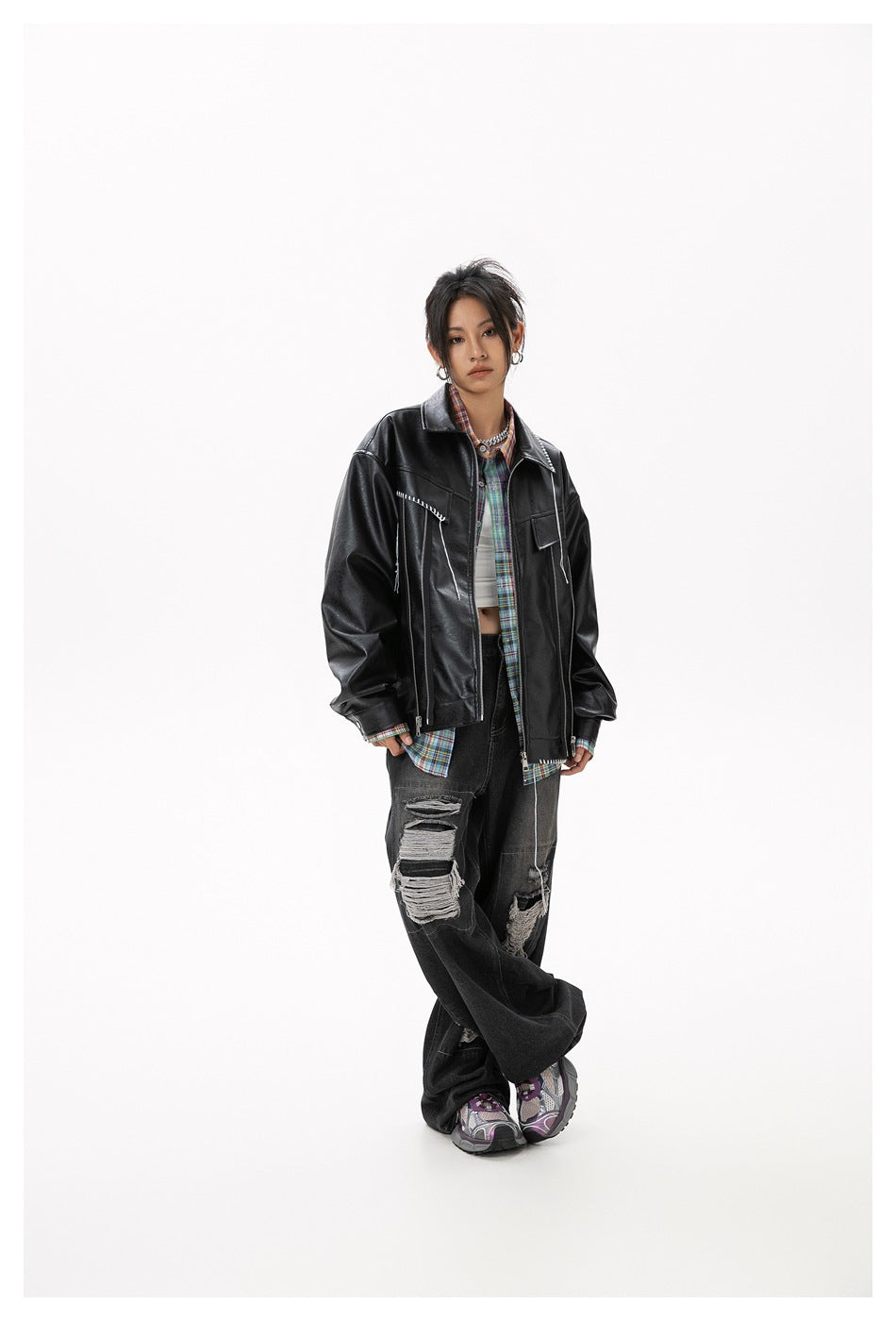 Model wearing an oversized black jacket with white stitch accents and a colorful plaid shirt.