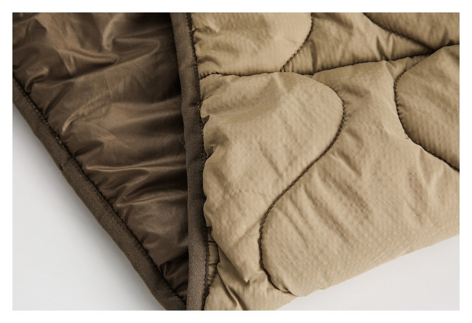Close-up of tan quilted outerwear, dark brown lining, and a bound seam.