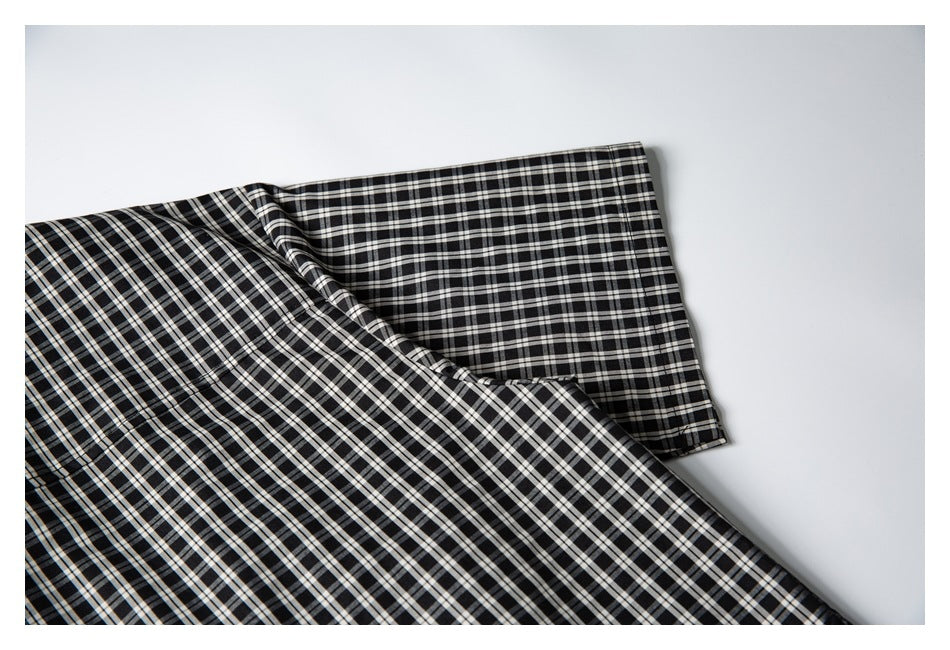 Close-up of a black-and-white plaid shirt sleeve and body laid flat.