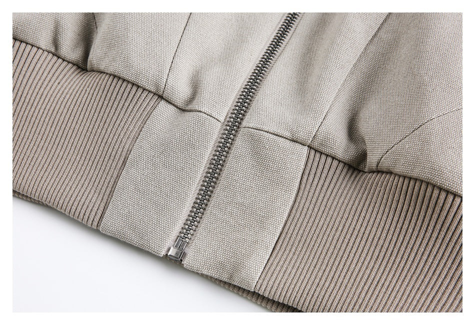 Close-up of the jacket's front zipper and ribbed hem in light taupe.
