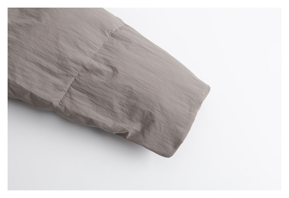 Close-up of the taupe padded jacket sleeve ending in a plain cuff.