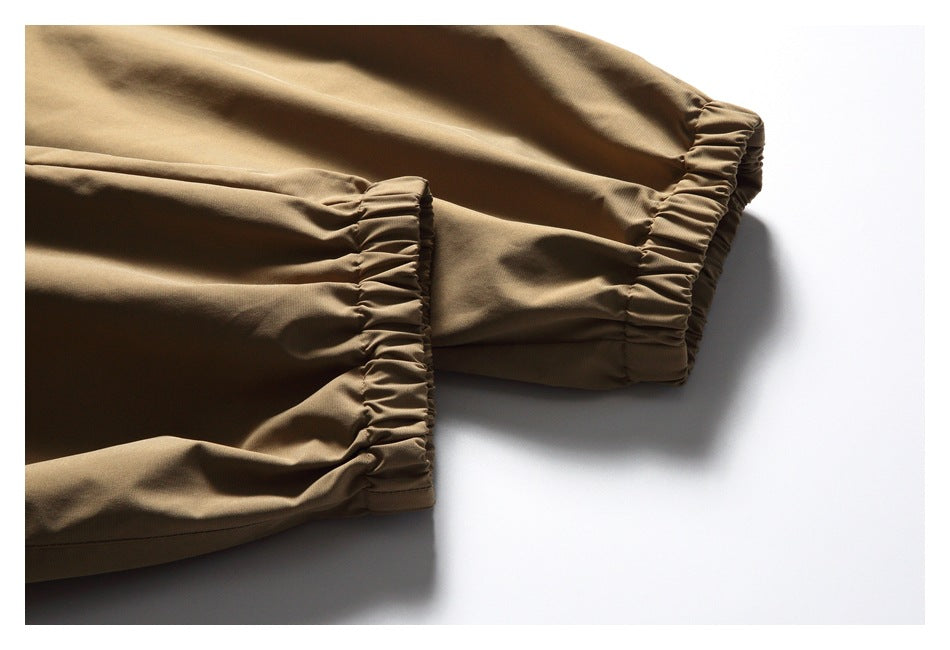 Close-up of brown trousers showing gathered elastic cuffs at the ends of the legs.