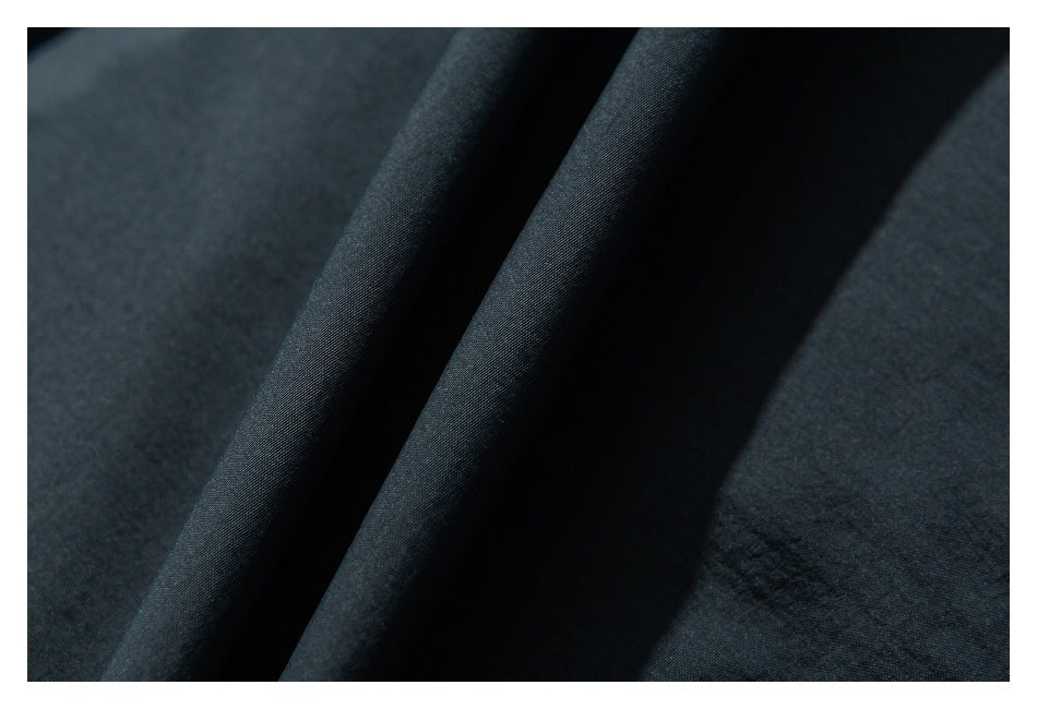 Extreme close-up of dark charcoal fabric folded to show its surface and drape.
