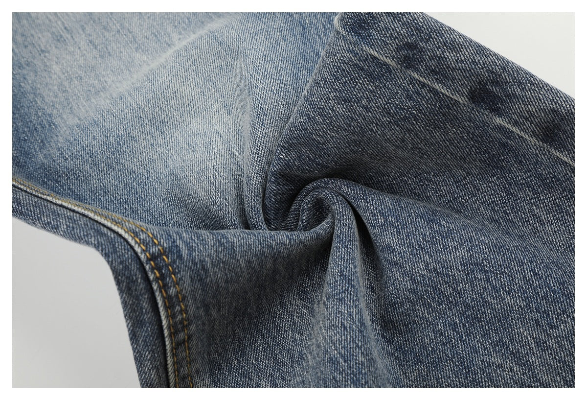Close-up of blue denim fabric folded to show its faded finish and texture.