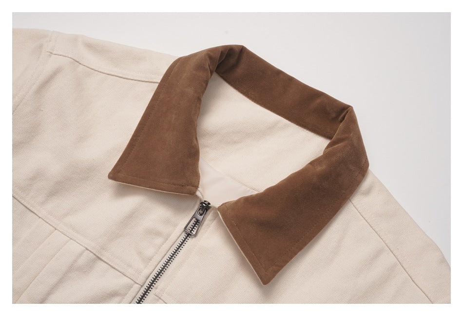 Close-up of a beige jacket with a brown pointed collar and metal front zipper.