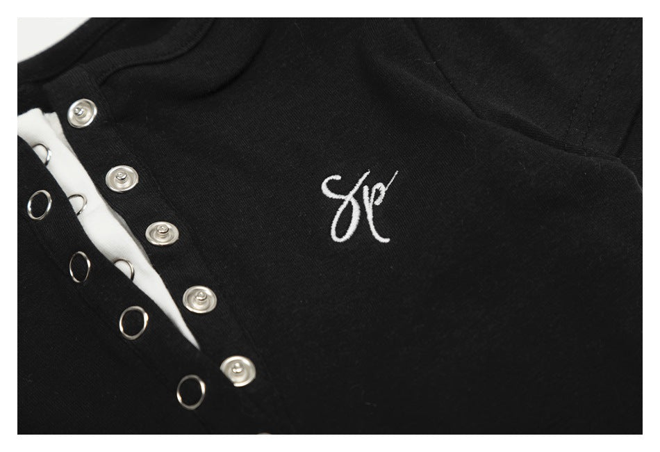 Close-up showing white script embroidery and the metal snap-button placket on the black top.