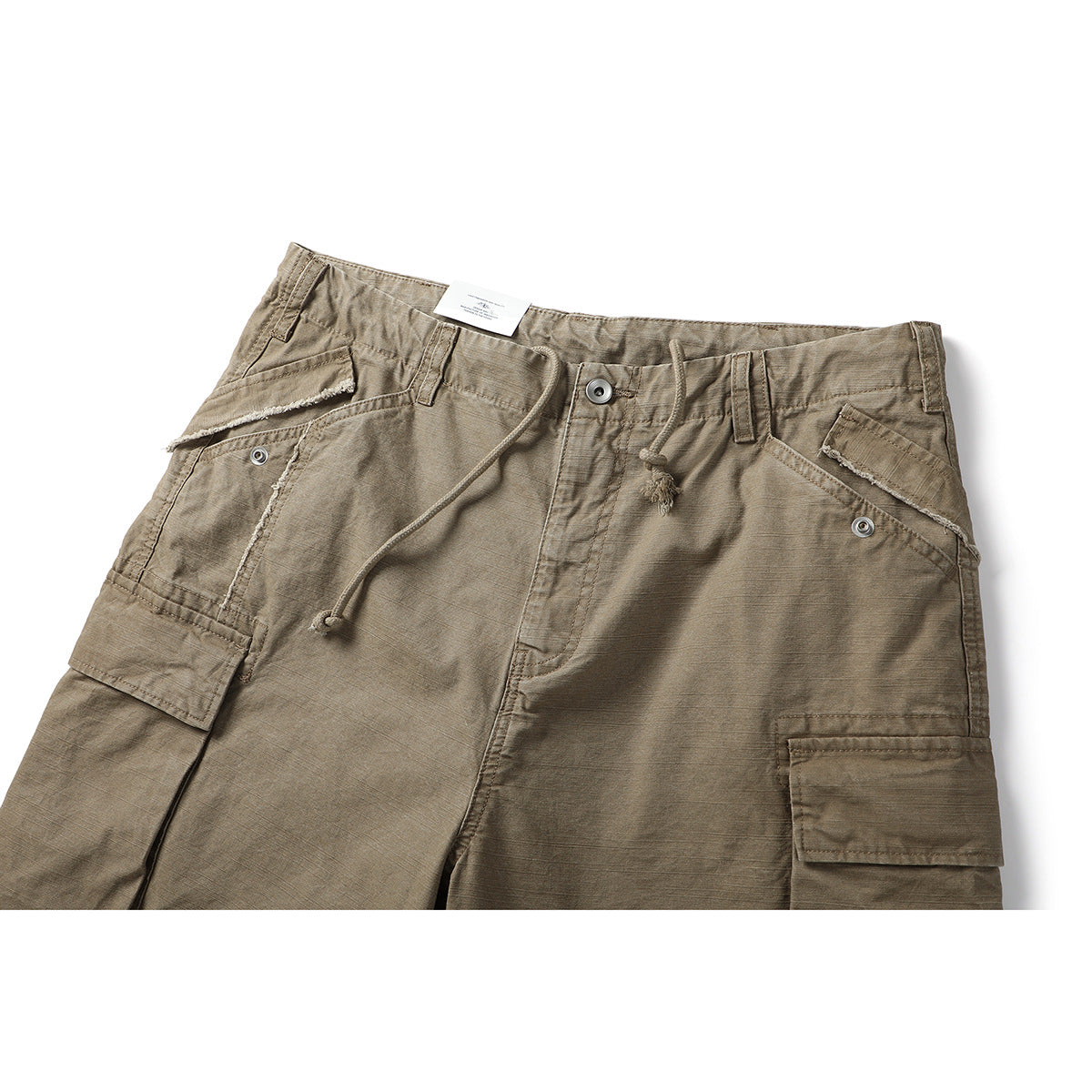 Close-up of taupe cargo shorts showing the drawstring waist, button closure and flap pockets.