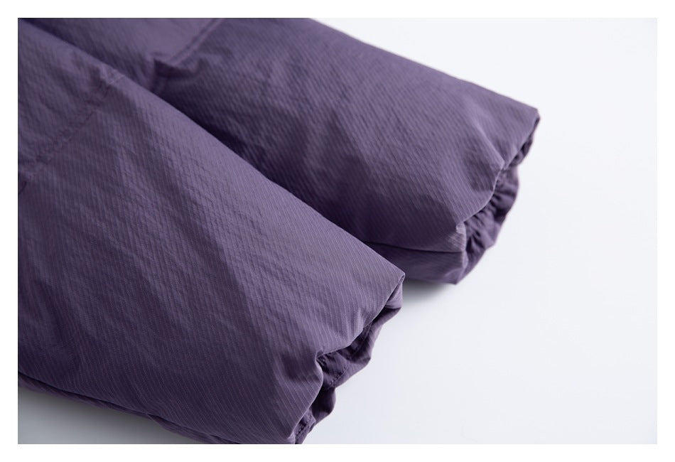 Close-up of two folded sections of dark purple garment fabric with fine vertical texture.