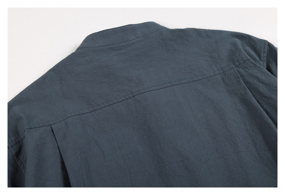 Close-up of the charcoal-blue garment's back shoulder yoke seam and upper back.