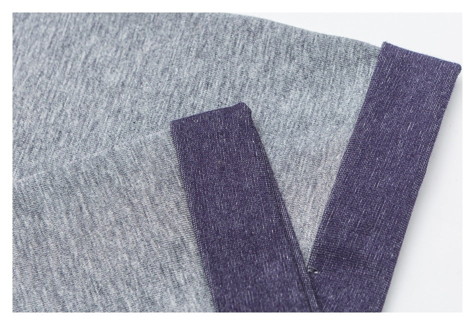 Close-up of heather gray fabric with a dark purple contrasting band and stitched edge.