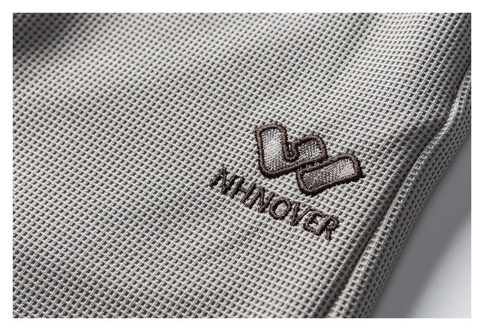 Close-up of light gray textured trousers with an embroidered WINOVER logo.
