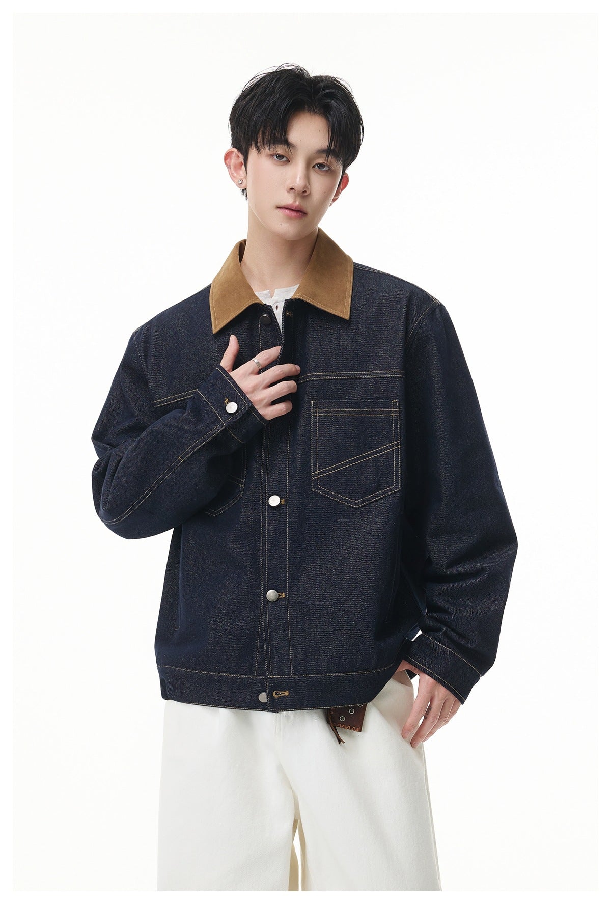 Front view of a model wearing a dark indigo denim jacket with a brown collar, metal buttons and chest pockets.