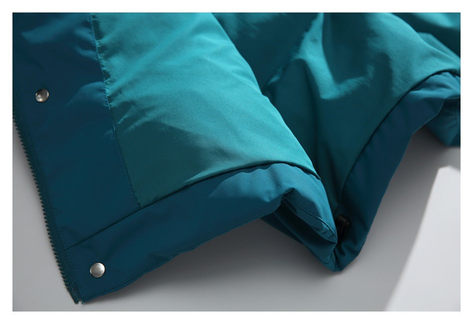 Close-up of a teal jacket hem with two metal snaps and a visible zipper edge.