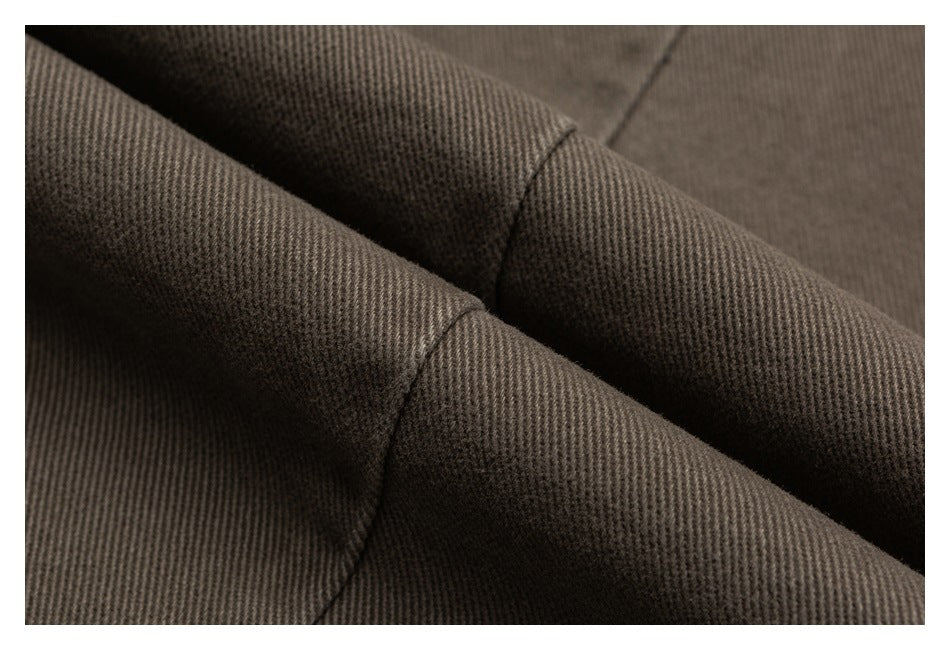 Macro view of dark gray twill fabric folded to show its diagonal weave and stitching.