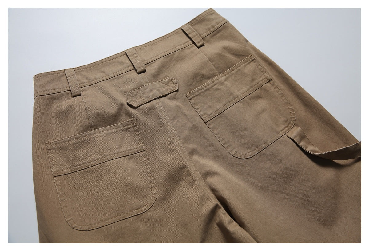 Angled view of brown utility trousers with belt loops, a buttoned fly and two large patch pockets.