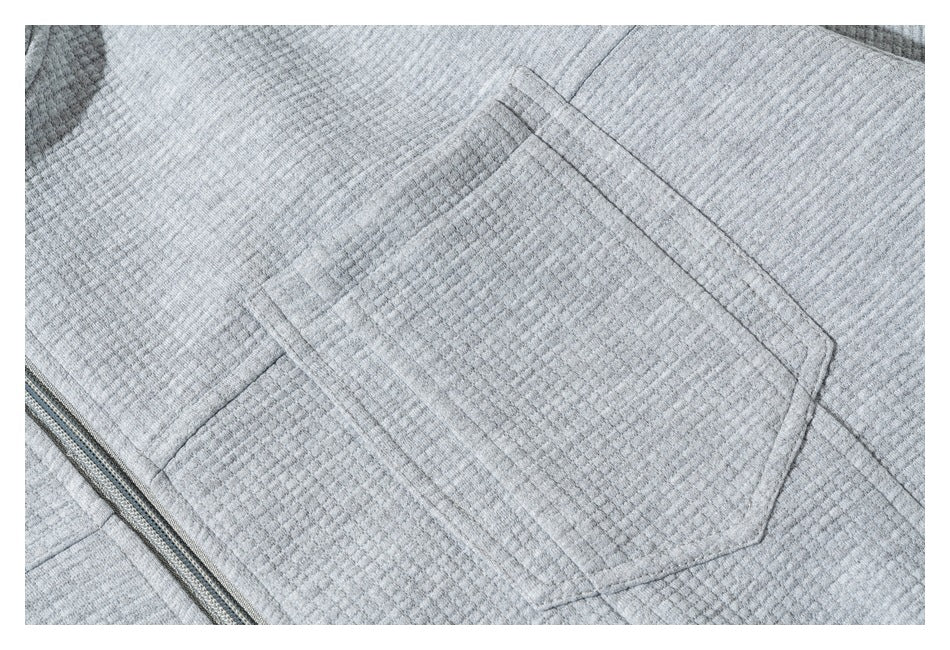Close-up of a patch pocket and zipper on the textured gray sweatshirt.
