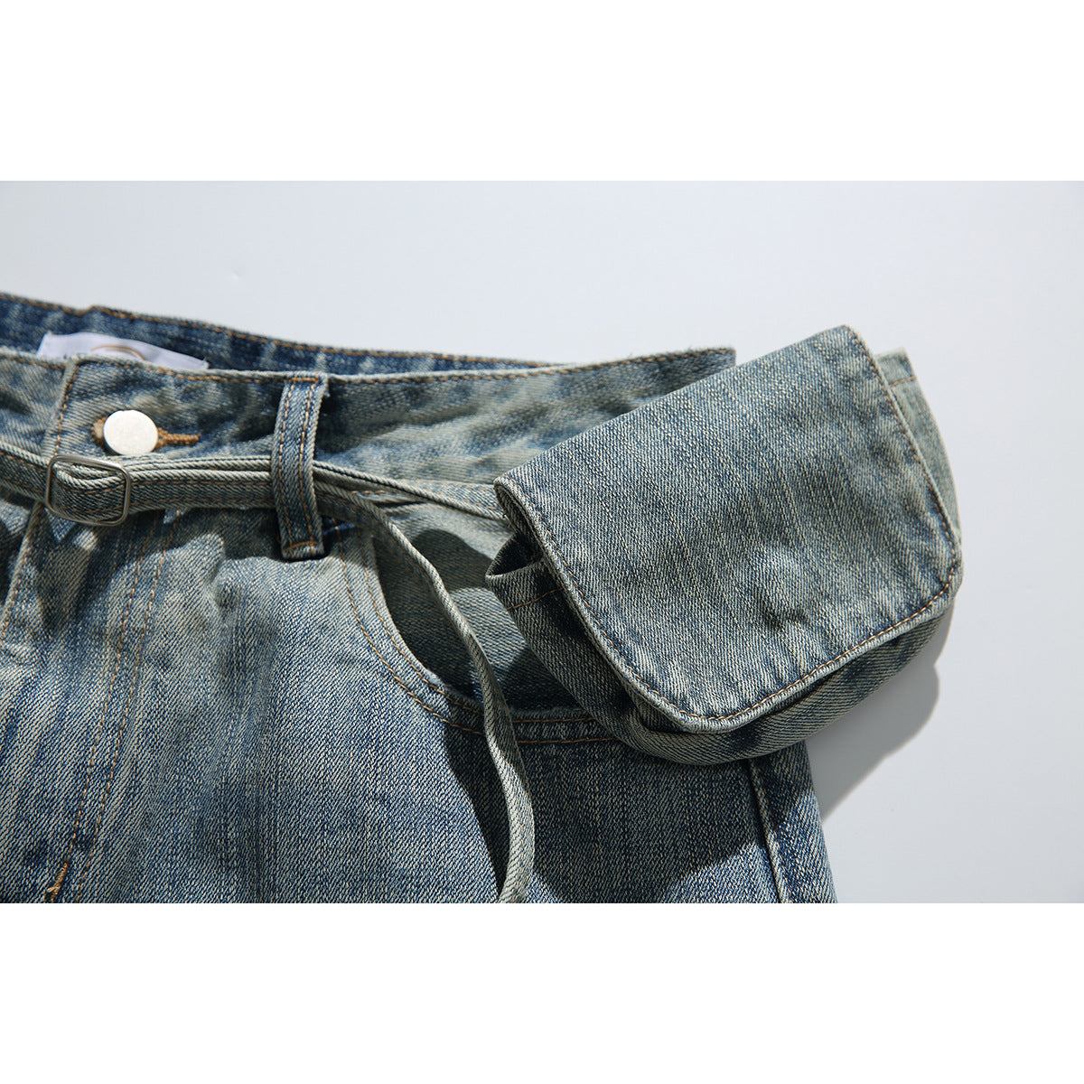 Close-up of the faded denim waistband, belt and attached pouch with a long hanging strap.