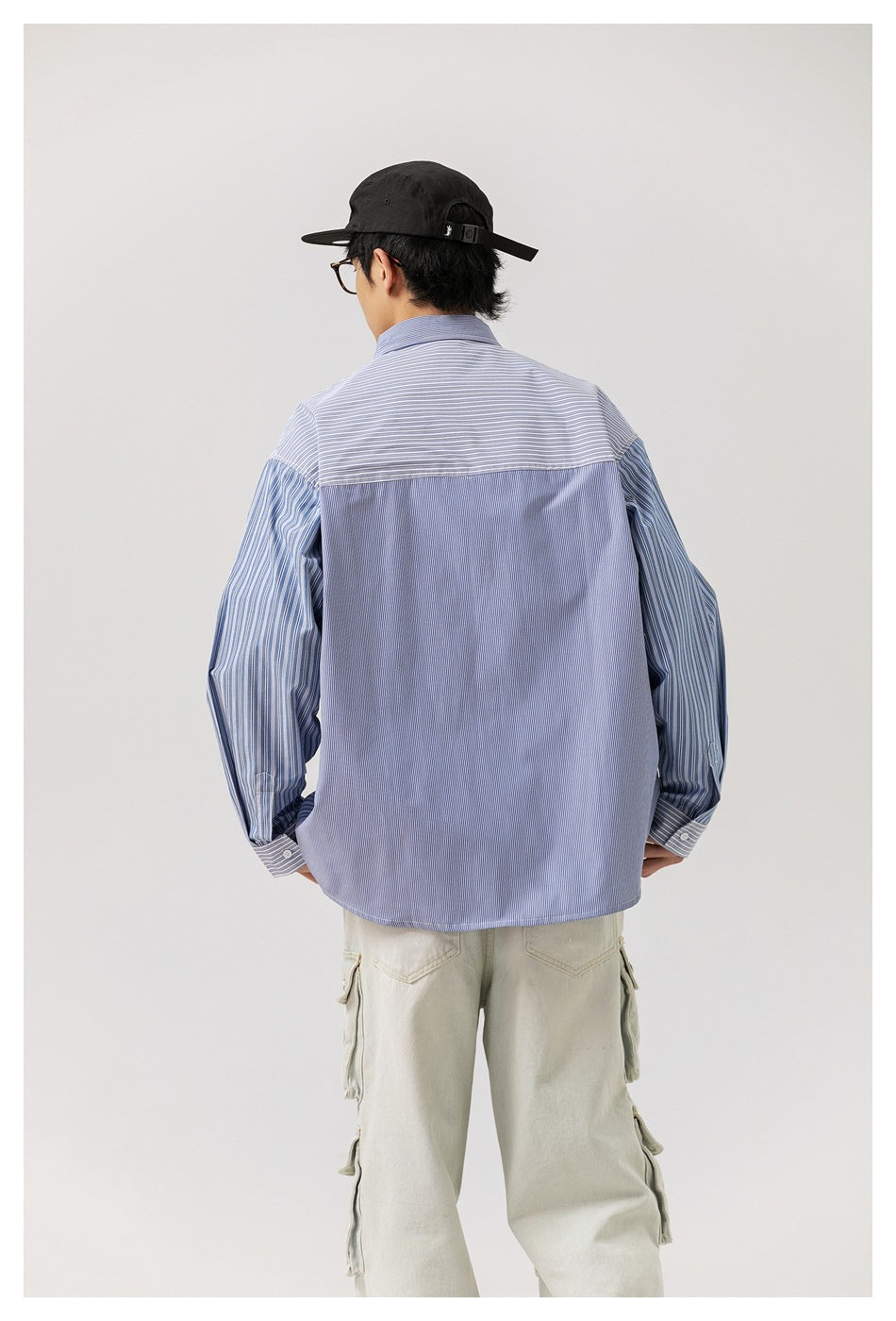 Back view of model wearing the blue striped patchwork shirt with horizontal-stripe yoke and light cargo pants