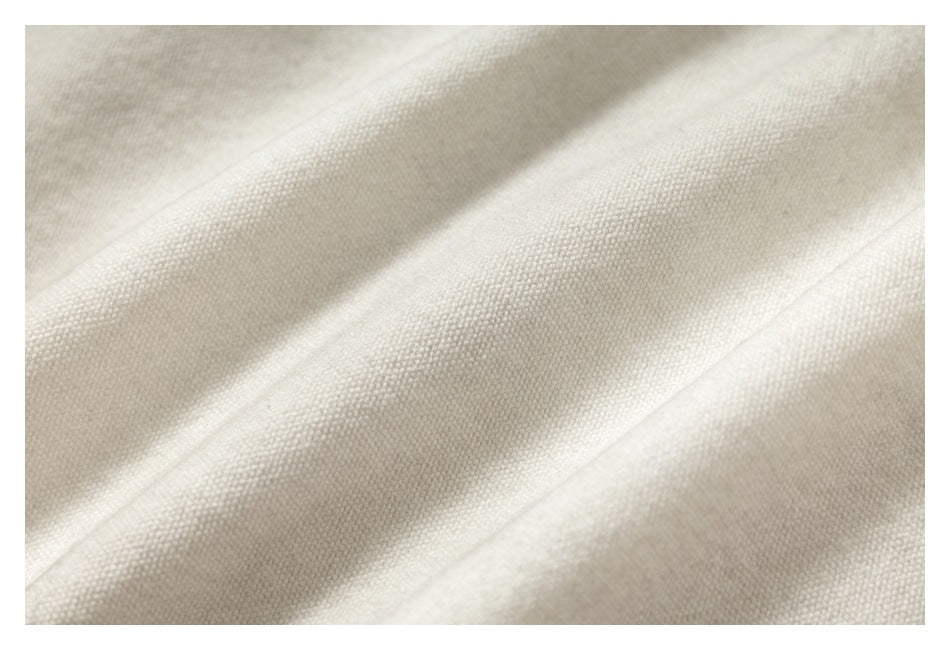 Close-up of ivory-colored fabric with a fine, tightly woven texture and soft folds.