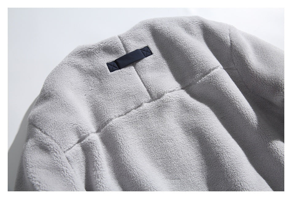 Close-up of a light gray fleece garment's upper back area with a small dark fabric loop.
