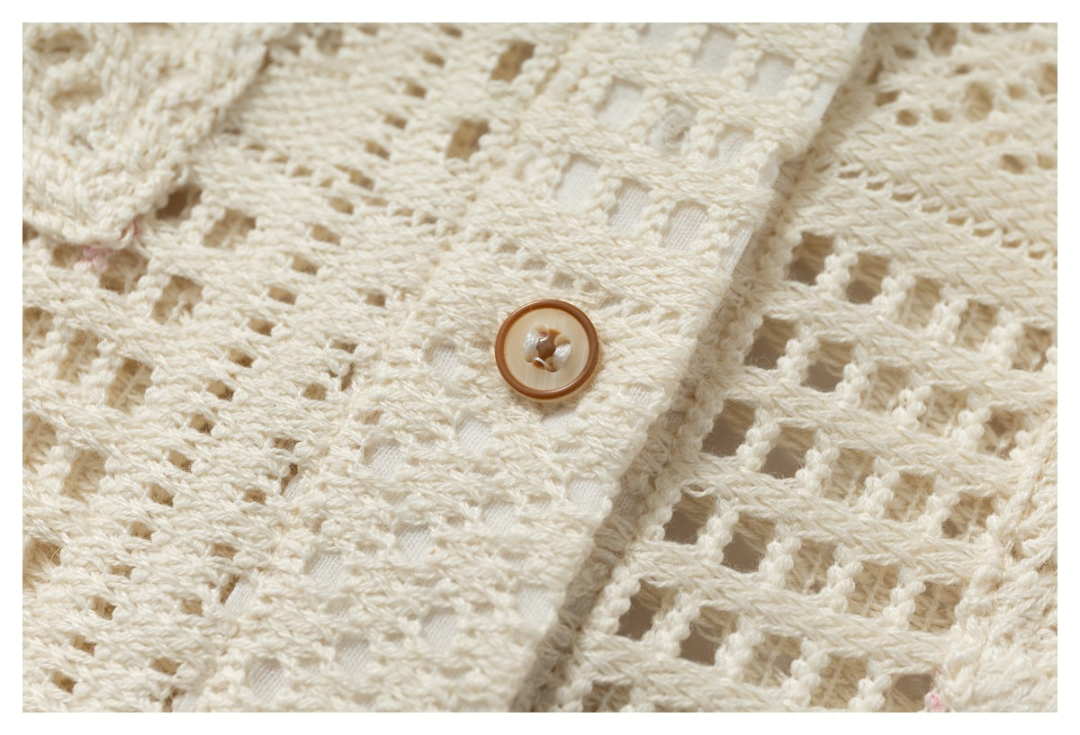Close-up of an ivory open-knit garment with a brown button and textured button placket.