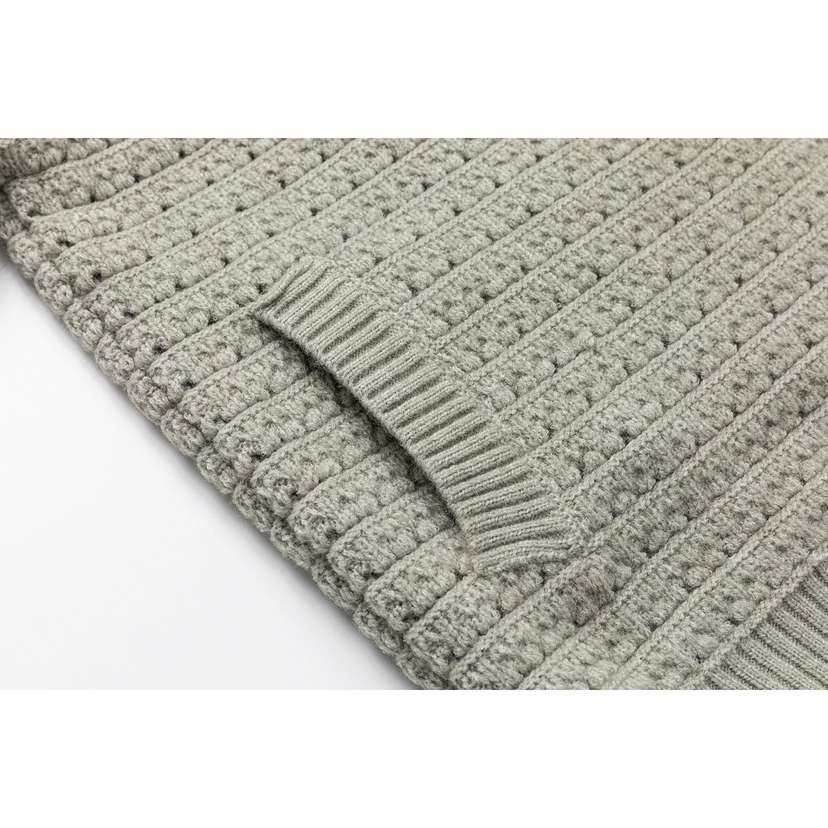 Close-up of the light gray cardigan's ribbed hem and textured knit pattern.