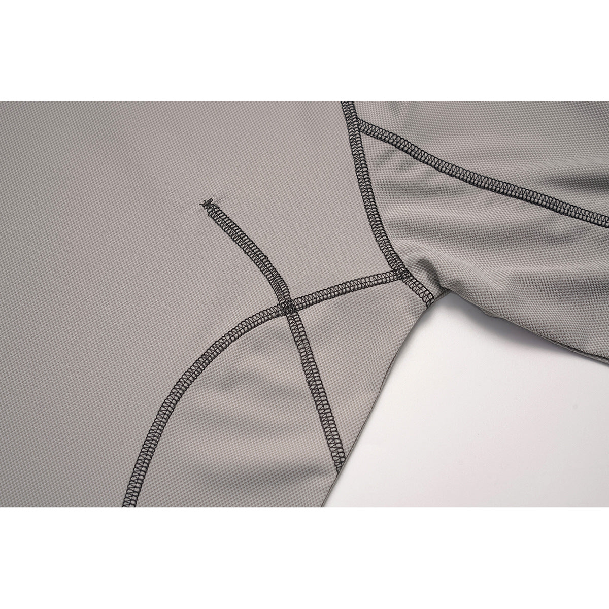 Close-up of curved panel seams and dark overlock stitching on the gray top.