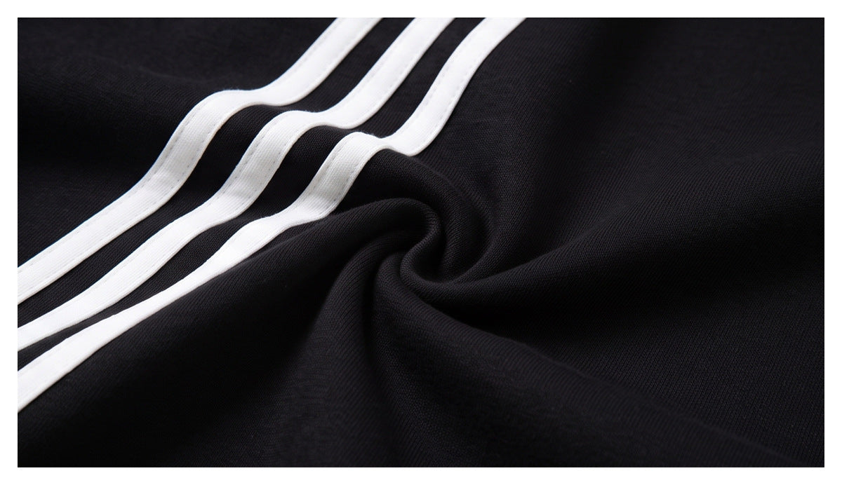 Close-up of three white stripes on gathered black jacket fabric.