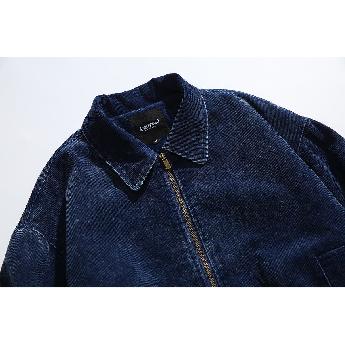 Close-up of a dark navy ribbed jacket collar, gold-tone front zipper, and sewn-in neck label.