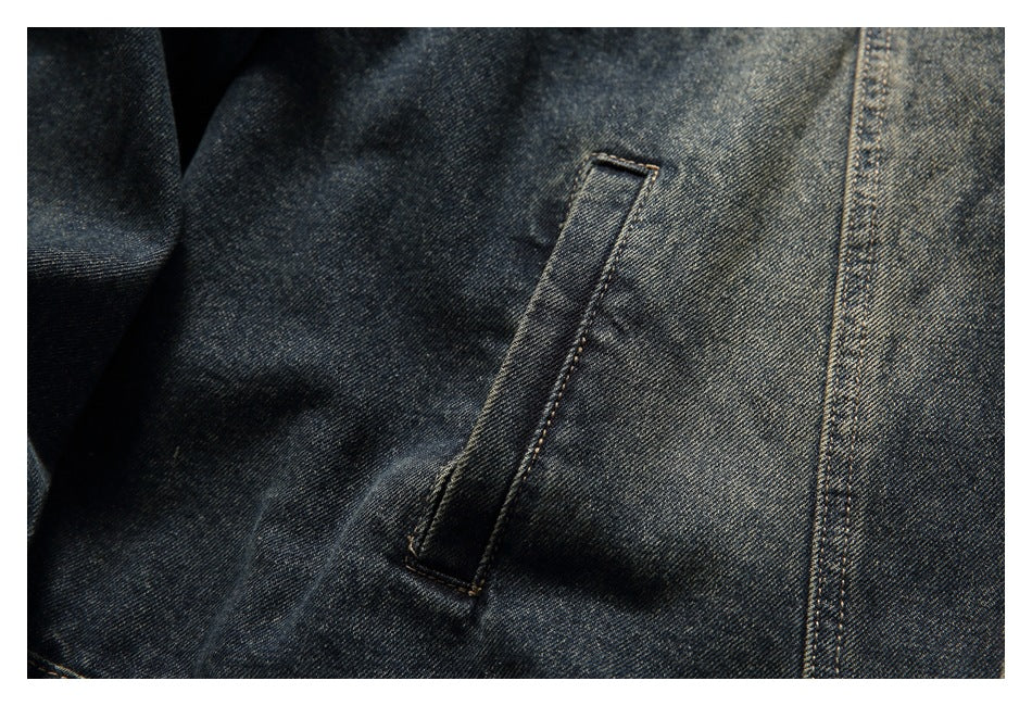Close-up of a vertical welt pocket and contrast stitching on dark charcoal denim.