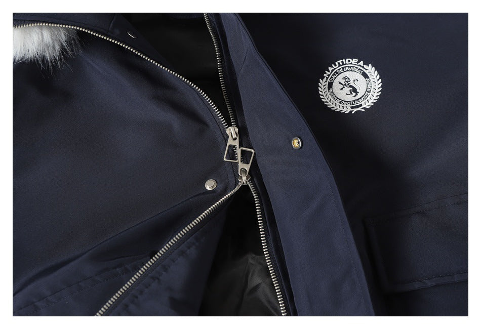 Close-up of a navy jacket with a silver zipper, snap fasteners, pale fur trim, and an embroidered chest emblem.