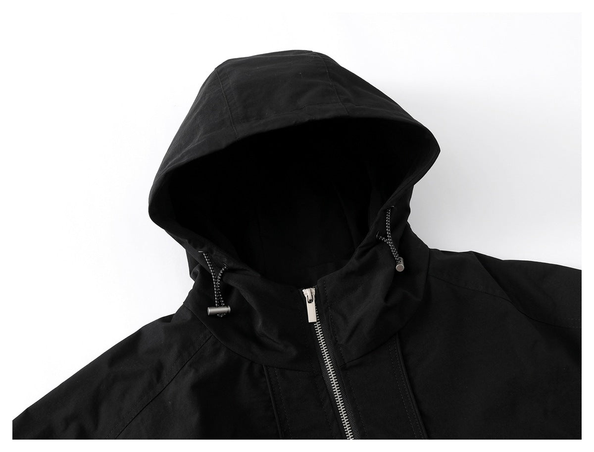 Close-up of a black jacket hood with drawcords, high collar and silver zipper.
