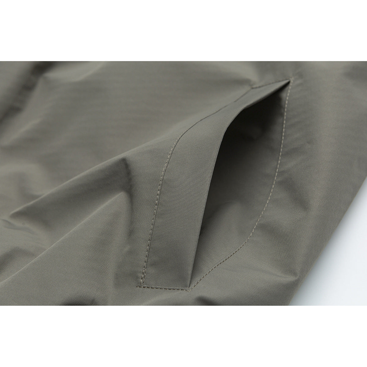Close-up of an angled welt pocket on olive-gray fabric.