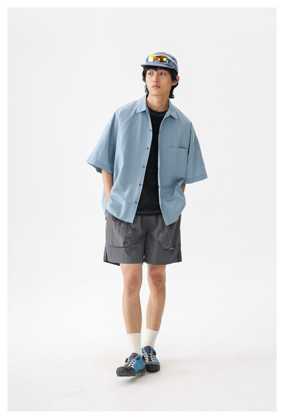 Front view of a model wearing a pale blue oversized short-sleeve button-up shirt with a chest pocket.