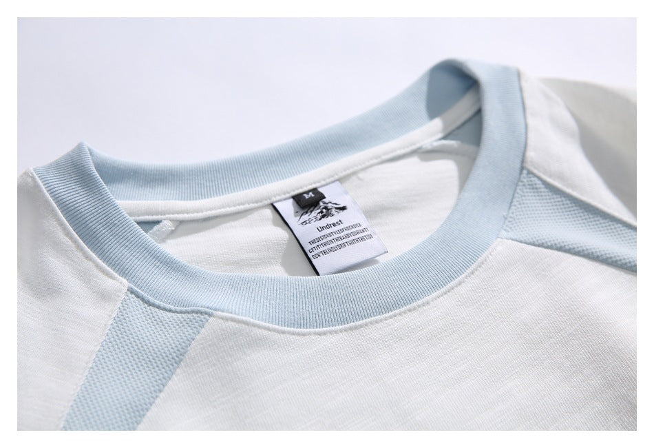 Close-up of a white T-shirt with a pale blue ribbed crew neck and inner neck label.