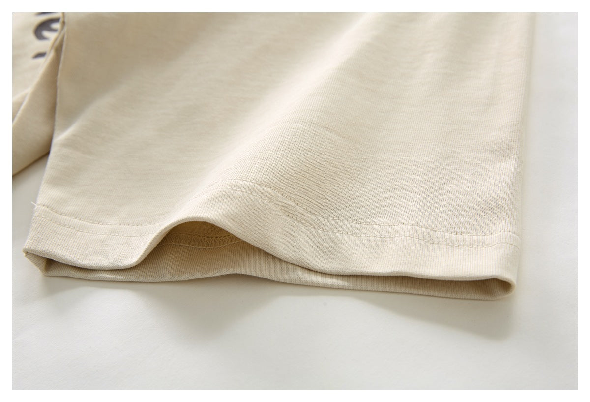 Close-up of the double-stitched hem on a cream shirt, with a small part of its printed design visible.