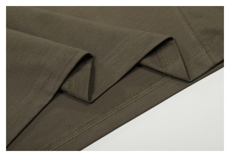 Close-up of olive-brown garment fabric showing a folded hem and overlock stitching.